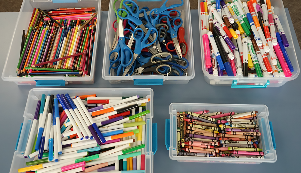Tubs full of different kinds of art supplies and writing utensils.