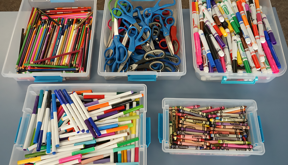 Tubs full of different kinds of art supplies and writing utensils.