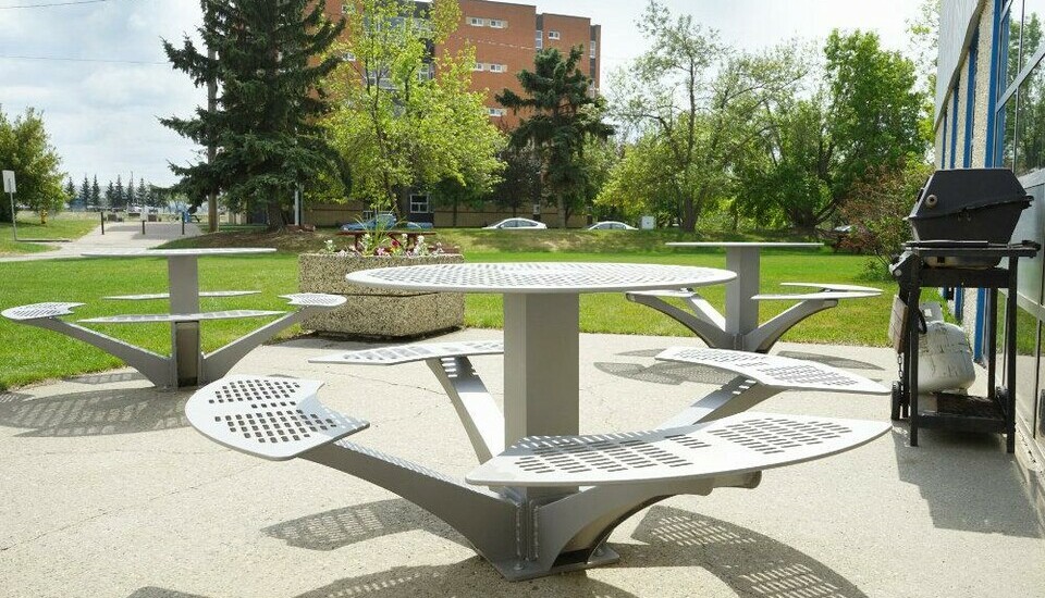 Round picnic tables on paved area outside of King's.