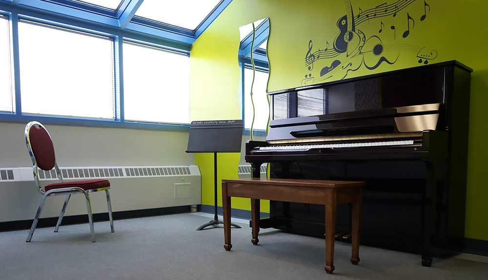 Brightly colored walls, large windows, a piano and music stands.