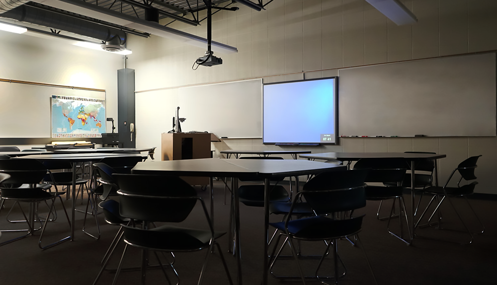 Large room with work tables, whiteboards and other technology for teaching.