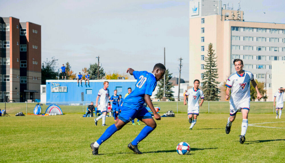 Men's soccer team with campus in background.