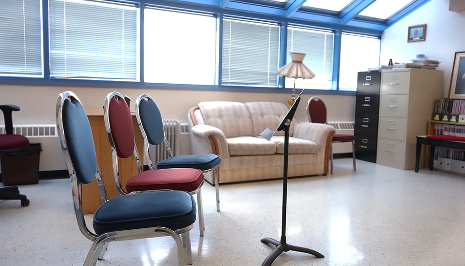 Large windows, comfortable seating and music stands in large room.