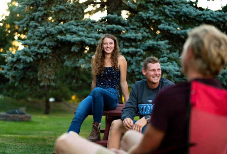 students hanging around outside by a fire on a warm summer evening