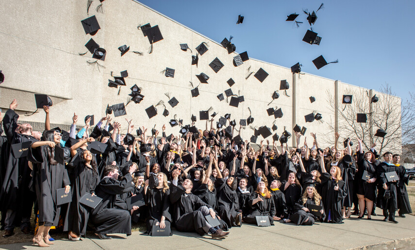 King's graduates celebrating by throwing their hats in the air.